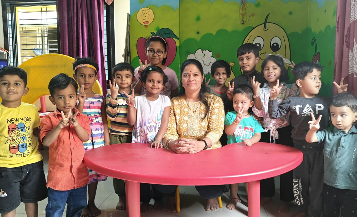 Smiling teacher with students at Utkarsha Play School, Pune
